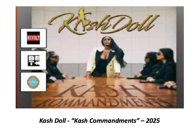 Still from Kash Commandments — Kash Doll in a white and black blazer at the head of a boardroom table surrounded by four seated women in dark suits.